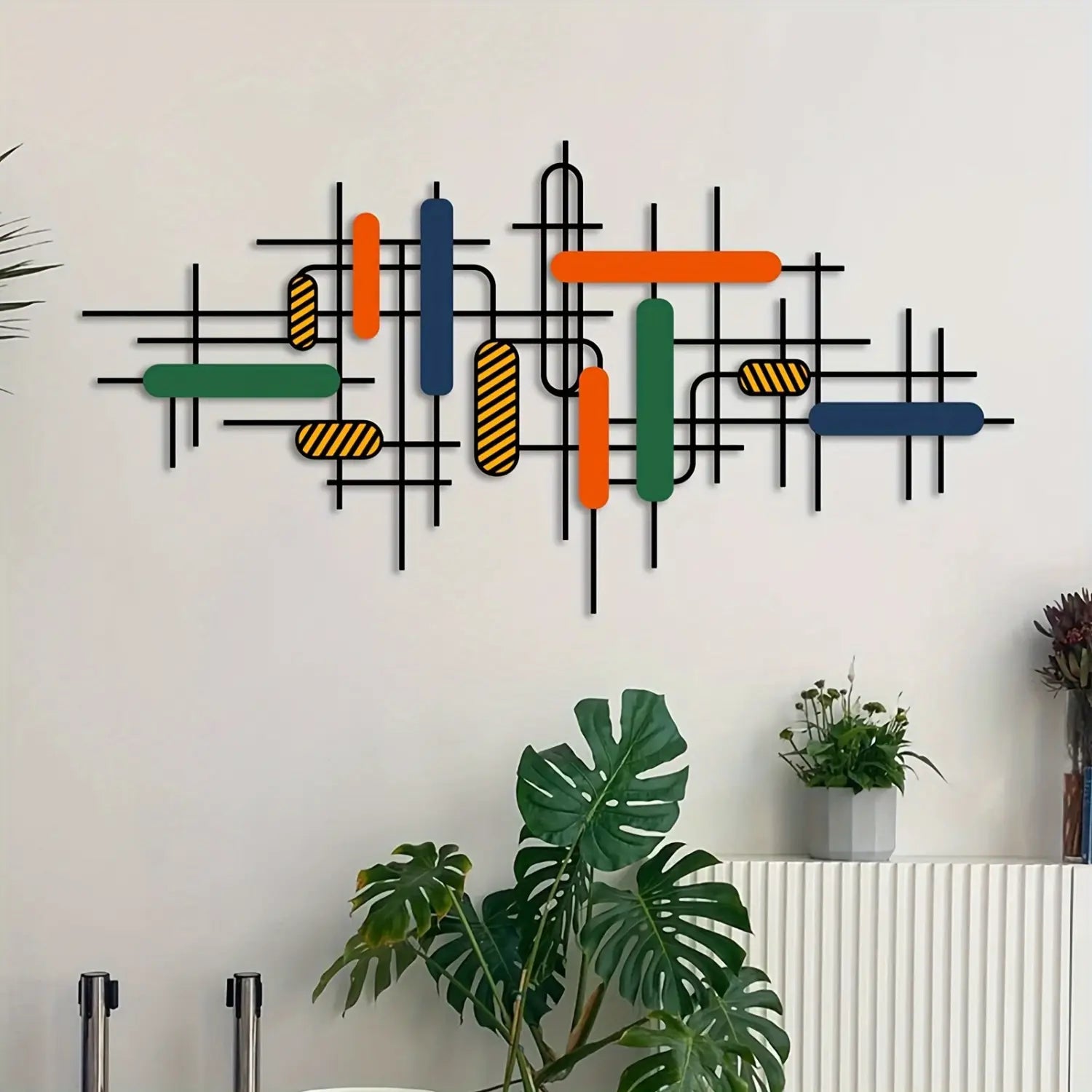 Modern geometric wall art with intersecting black metal bars and colorful rectangular accents in orange green blue and yellow striped patterns as vibrant wall decor.