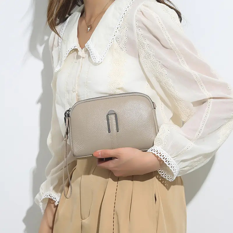 Beige strukturierte Umhängetasche-Clutch aus echtem Leder für Damen mit elegantem silberfarbenem Metallschnallenverschluss und verstellbarem Riemen.