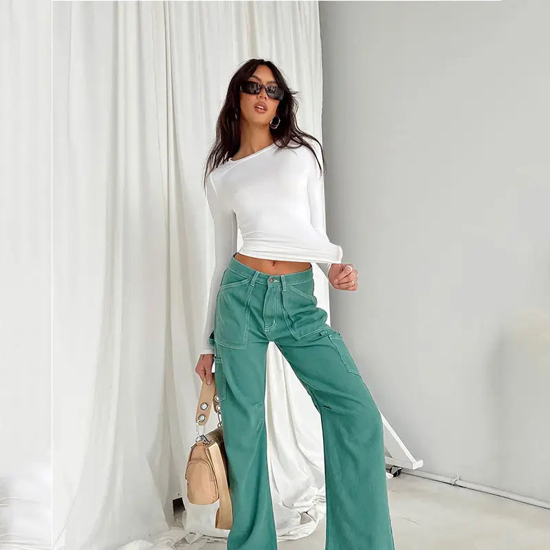 Pantalones cargo color verde azulado de pernera ancha combinados con una blusa corta ajustada tipo slim fit para mujer, con mangas largas fruncidas, que muestra un atuendo casual con estilo.