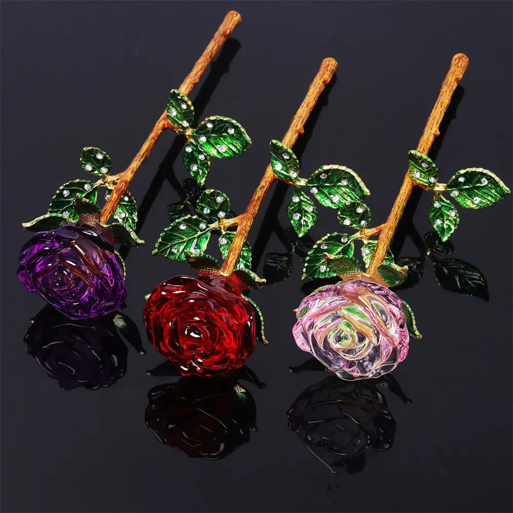Three ornate crystal glass roses in purple red and pink with jeweled green leaves on golden stems for a Valentine’s Day gift.