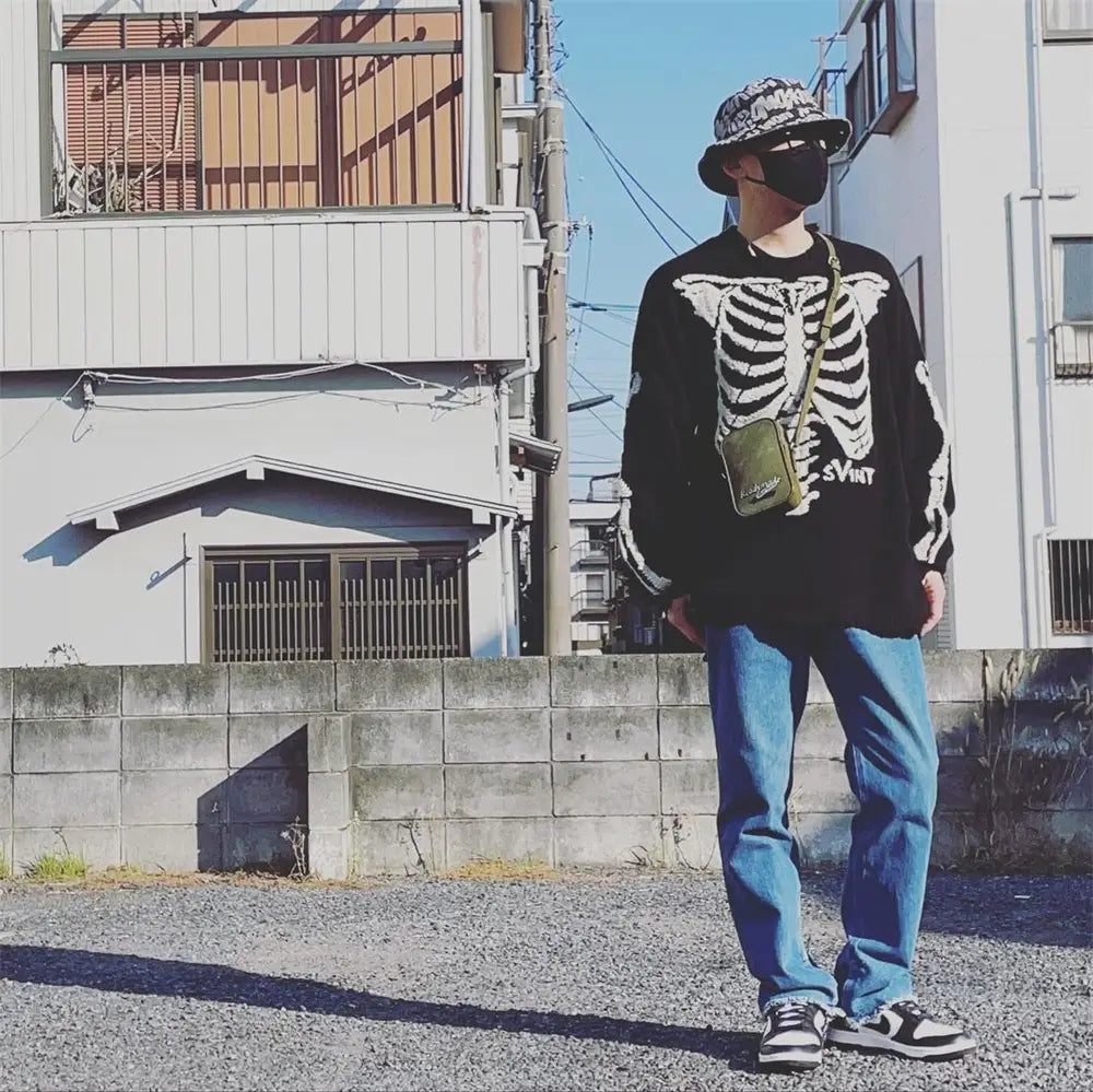 「Sin Embroidered Black Oversized Knit Sweater」と題された長袖のフロントパネルに、大きな白いスケルトンのグラフィックデザインを施したブラックのオーバーサイズニットセーター。