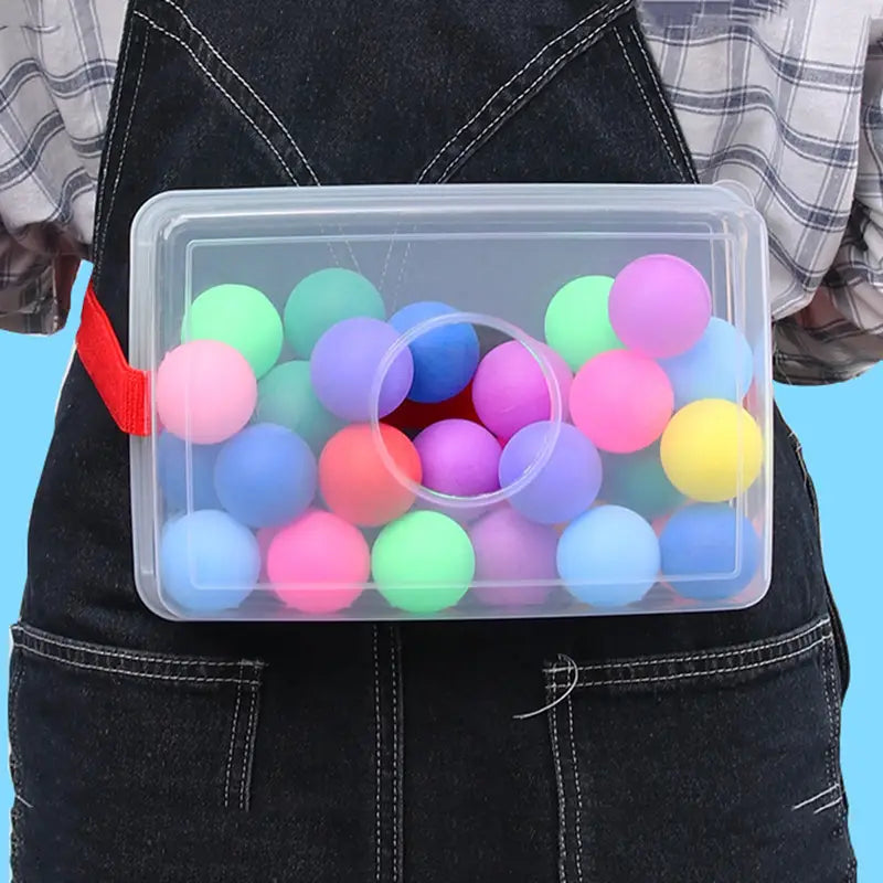 Clear plastic storage box with red strap containing colorful foam balls in pink blue green purple and yellow for the shaking swing balls party game set.