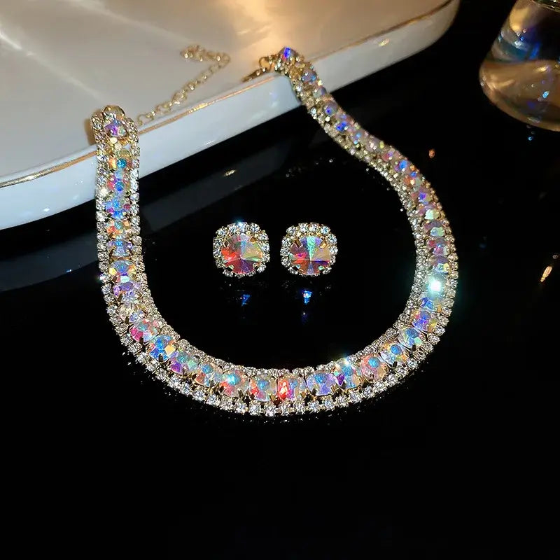 A sparkling iridescent pink ab crystal necklace and earring set featuring multicolored crystals and smaller clear stones set in gold-toned metal for wedding jewelry.