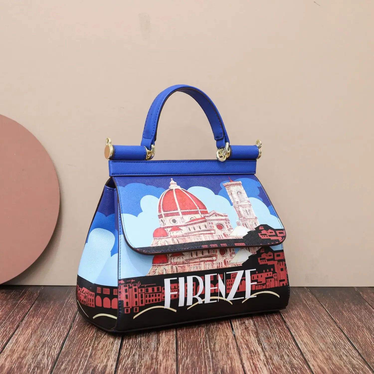 Sac bandoulière en cuir vintage, art raffiné, en bleu éclatant, avec une illustration détaillée de l’architecture emblématique de Florence, ses dômes rouges et sa quincaillerie ton or.