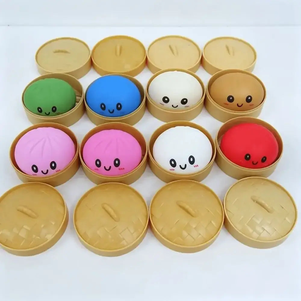 Boules anti-stress souples rondes et colorées à l’effigie d’une boulette de dumpling souriante, en matériau souple, dans des paniers vapeur en plastique, conçues pour un usage de jouet sensoriel et pour le soulagement du stress.
