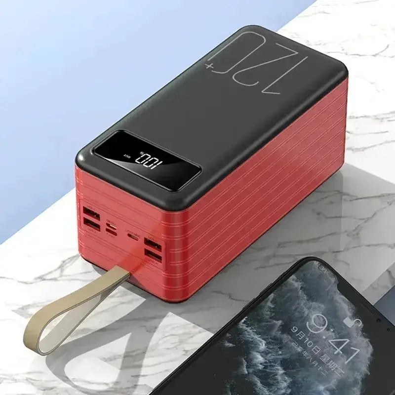 Portable power bank in red and black with a digital display showing 10.2v, multiple usb ports, and a beige wrist strap attached to the edge.
