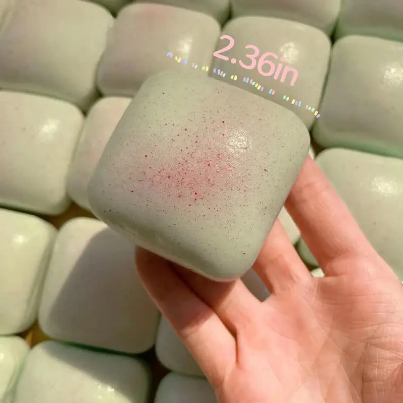 a pale green matte-finish slow rising squishy mini toast fidget toy with a subtle pinkish speckled pattern on its square surface