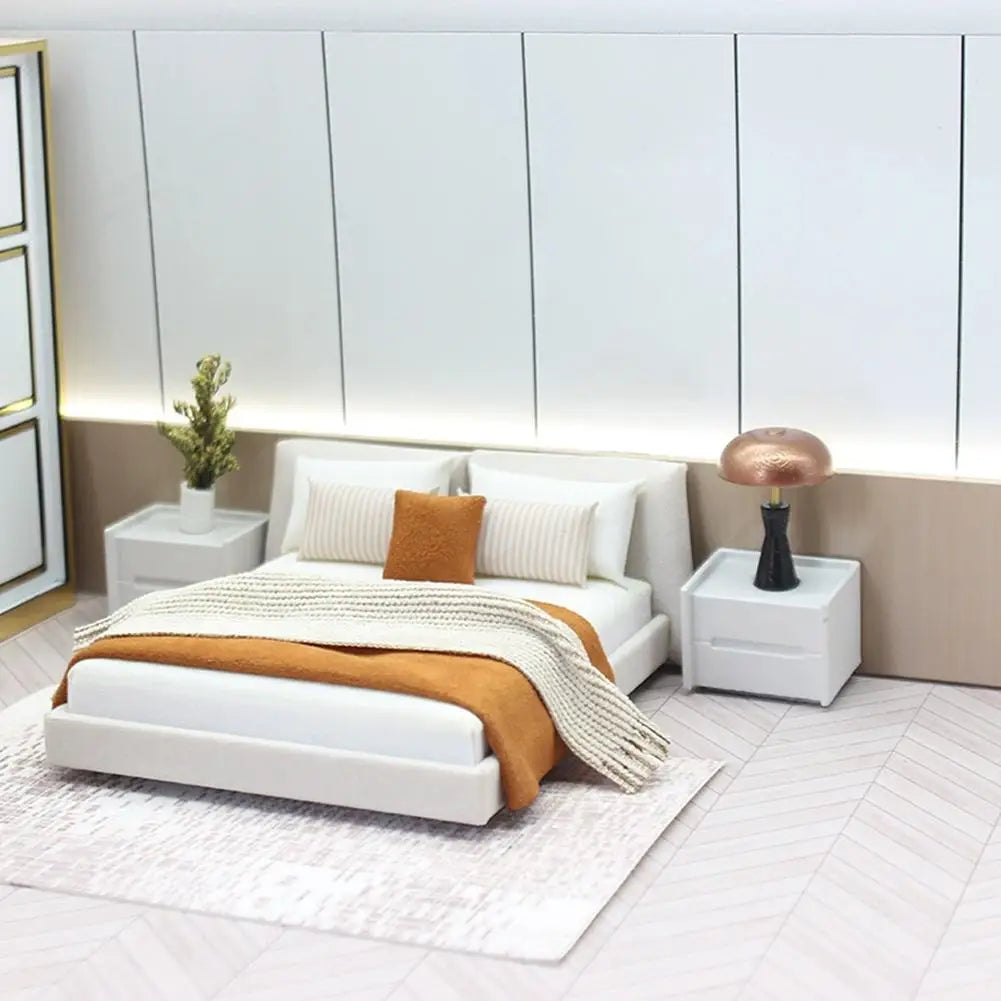 White miniature dollhouse double platform bed with cream style bedding featuring an orange throw blanket and striped pillows.