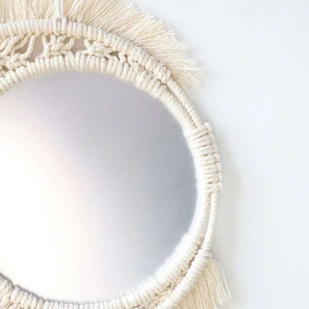 Cream-colored macrame wall mirror with fringe detailing for living room home decor.