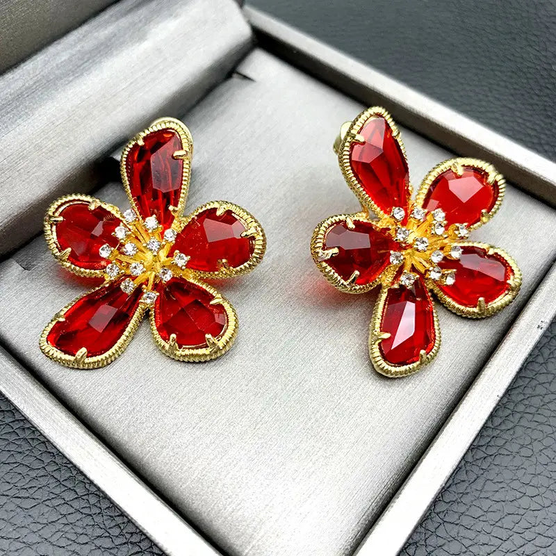 赤いクリスタルの花びらを配し、金色調の金属セッティングと、中心にきらめくクリアのラインストーンをあしらった、エレガントなゴールドフラワークリスタルスタッドピアス。