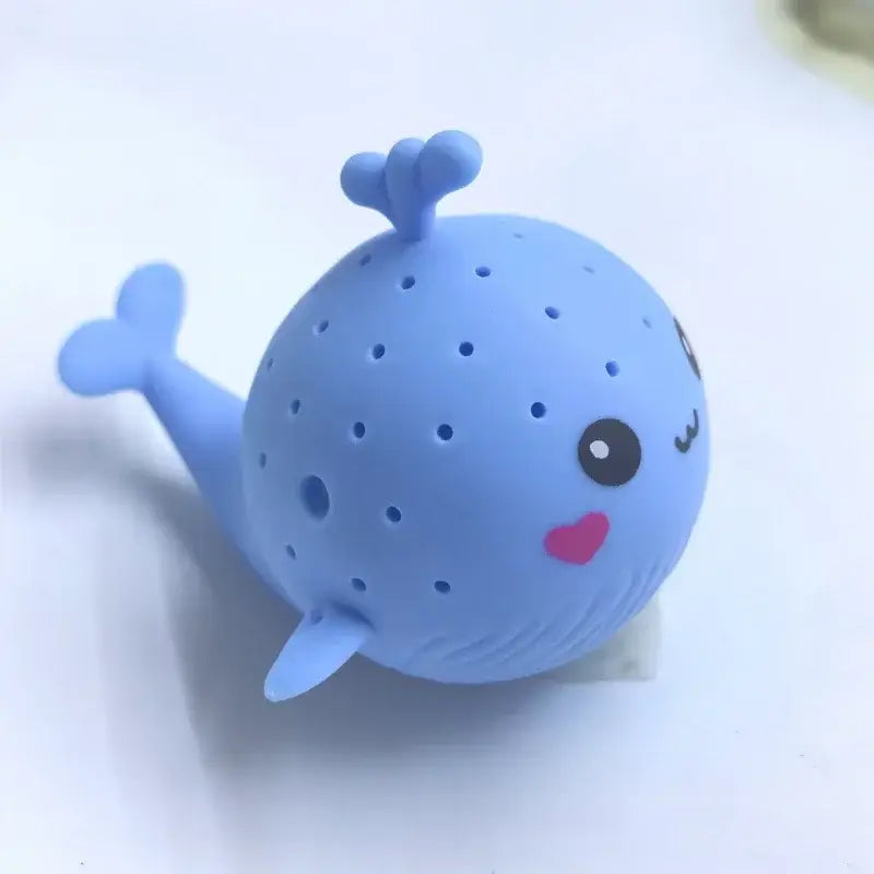 Ein hellblauer Silikon-Blauwal geformter Teeei-Aufgussbehälter mit perforiertem Körper, niedlicher Miene und pinkfarbenem Herznäschen, gestaltet als Blauwal-Badeschwamm-Wasser-Spielzeug für Kinder.
