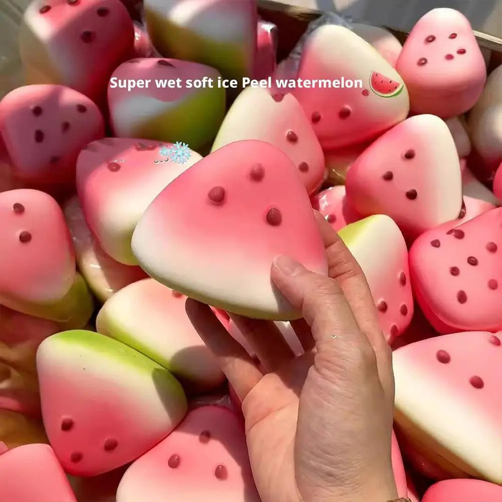 Ein Hand hält einen rosa-weißen Farbverlauf-Wassermelonen-förmigen Soft-Squeeze-Gegenstand zur langsamen Steigerung mit roten Punktdetails, entworfen als taktiler Stressabbau.