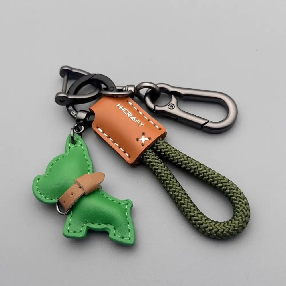 Green leather French bulldog keychain featuring a tan belt detail and an olive green braided rope strap.