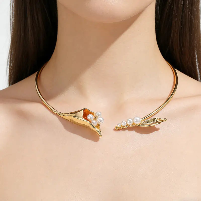 Chokerkette mit goldfarbenem Ton, florales Design mit Muschel- und Blattmotiv, verziert mit weißen Perlen für einen eleganten Auftritt.