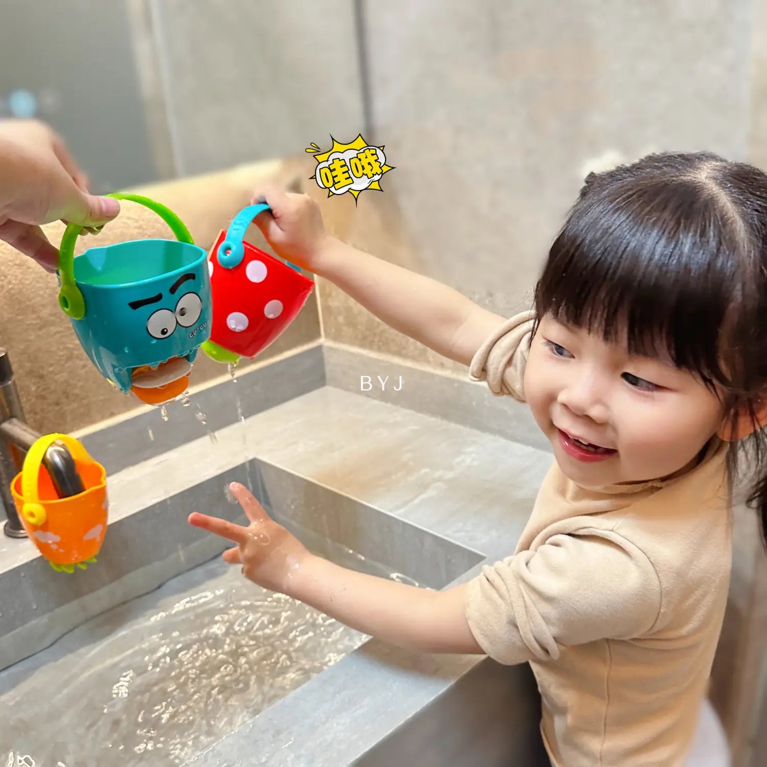 Blau- und rote Kunststoff-Badewannen-Eimer für Babys mit Wassersprühfunktion, mit Cartoon-Gesichtern und Griffen für eine einfache Handhabung.