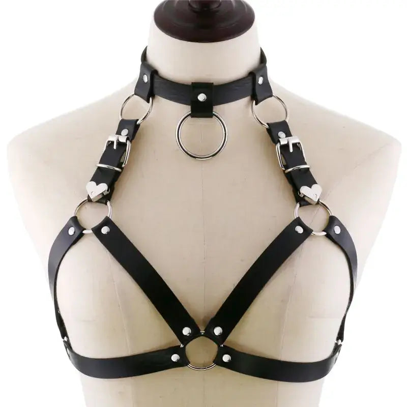 Black goth body harness made of faux leather with silver metal rings and heart-shaped buckles designed as goth body jewelry.