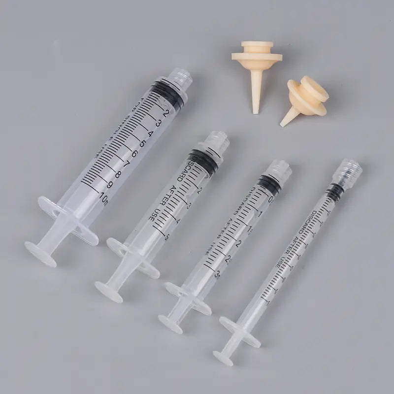 Pet oral syringe feeding set with clear plastic syringes featuring black measurement markings, white plunger handles, and beige rubber tips with silicone nipples for feeding.