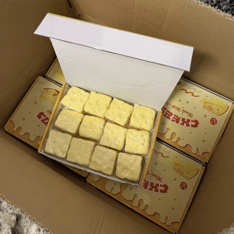 yellow square-shaped cheesecake fidget toys measuring 6cm by 6cm wrapped in clear plastic and packaged in a cardboard box with cartoon cheese branding for stress relief