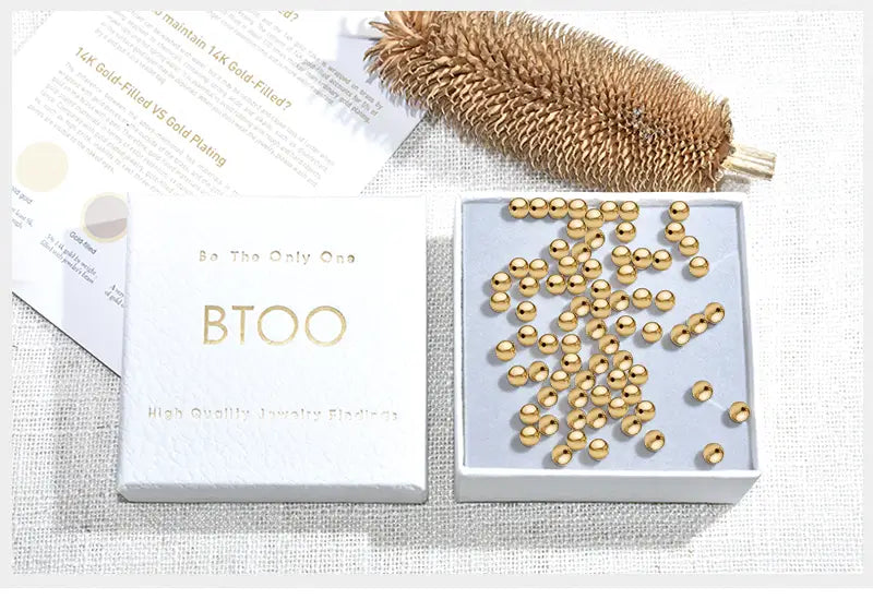 a collection of small round golden 14k gold-filled beads in a white btoo box complementing the leather hole punch beading awl wood handle steel tool product