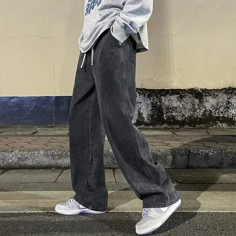 Jeans pour hommes à jambes larges, coupe ample, denim style streetwear coréen, avec un denim gris foncé légèrement délavé, une coupe décontractée à jambe droite et des cordons de serrage blancs à la taille.