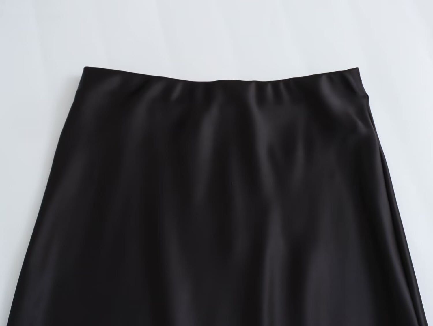 Jupe midi en satin noir à finition lisse et brillante et design long élégant à taille haute.