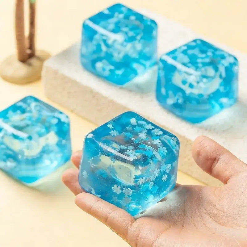 ein durchscheinender blauer Eiswürfel mit Schneeflocken-Motiv zur Stressreduktion aus Harz, mit eingebetteten weißen Schneeflockenmuster, von vorne sichtbar.