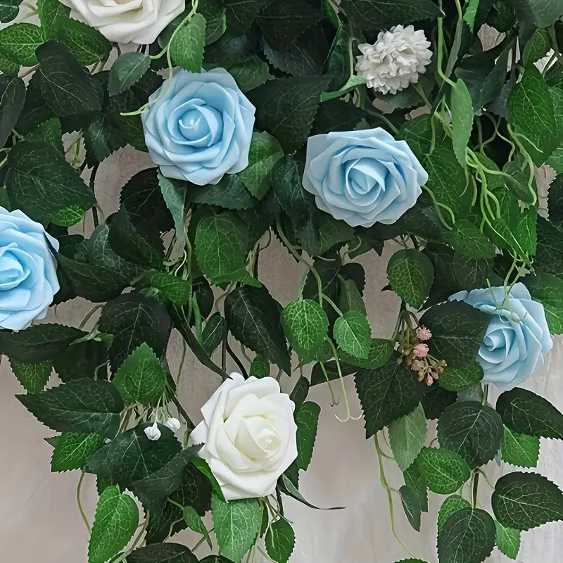 Des roses de fleurs artificielles avec des tiges pour la décoration, comprenant une vigne florale artificielle ornementale, avec des roses en mousse bleu clair et blanches entremêlées de feuilles vertes luxuriantes.