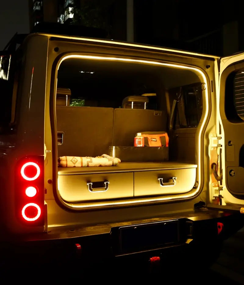 the illuminated rear of a beige suv with an open cargo area showing built-in drawers and compartments featuring car trunk lighting fit for a modified auto trunk in the baic 212 t01 2024 model