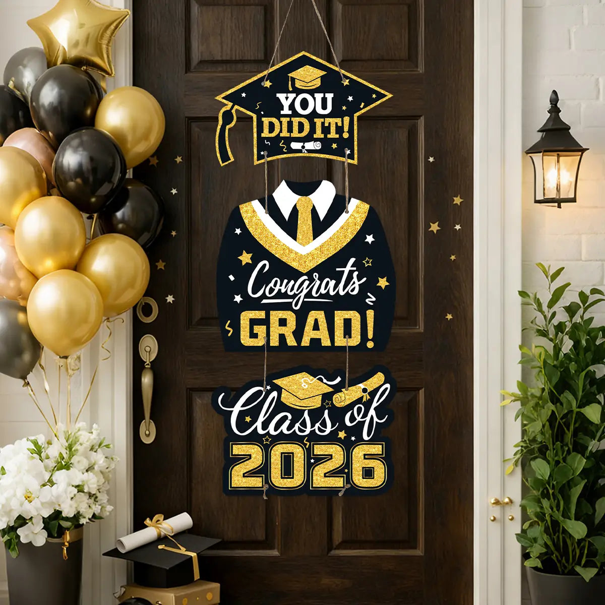 Gold and black graduation-themed hanging door decoration featuring a cap, gown, tie, and class of 2026 text for celebratory events.