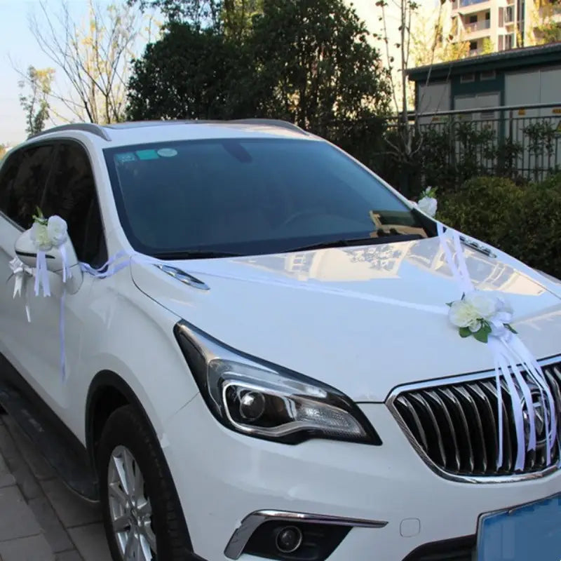 SUV Buick Encore blanc décoré de décorations florales artificielles blanches et de rubans destinés à l’ensemble de décoration de voiture de mariage.