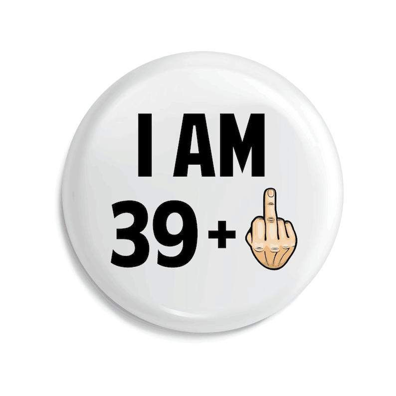 badge de broche émaillé circulaire blanc avec du texte noir indiquant « j’ai 39 ans et plus » et un geste de doigt en forme de doigt de bande dessinée, conçu comme un cadeau amusant d’anniversaire marquant une étape d’âge.