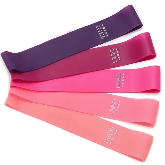 Ensemble de cinq bandes de résistance colorées aux teintes violet, rose et corail avec un marquage blanc indiquant différents niveaux de résistance pour une utilisation en fitness et en pilates.
