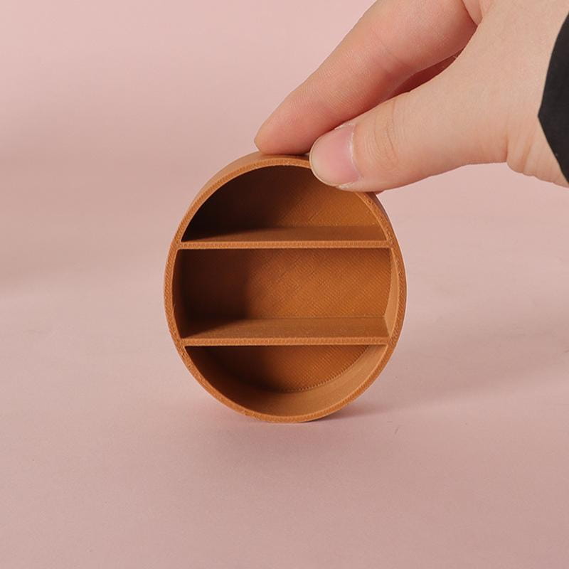 Un petit organisateur circulaire en cuir, avec trois compartiments horizontaux, fabriqué à partir d’un matériau de couleur beige, destiné à être utilisé dans une étagère d’exposition miniature en bois pour meuble mural de poupée.