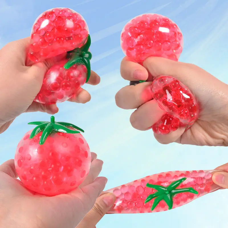 red strawberry-shaped squishy tomato stress relief toy with green leafy top and translucent gel bead filling for squeezing and stress relief