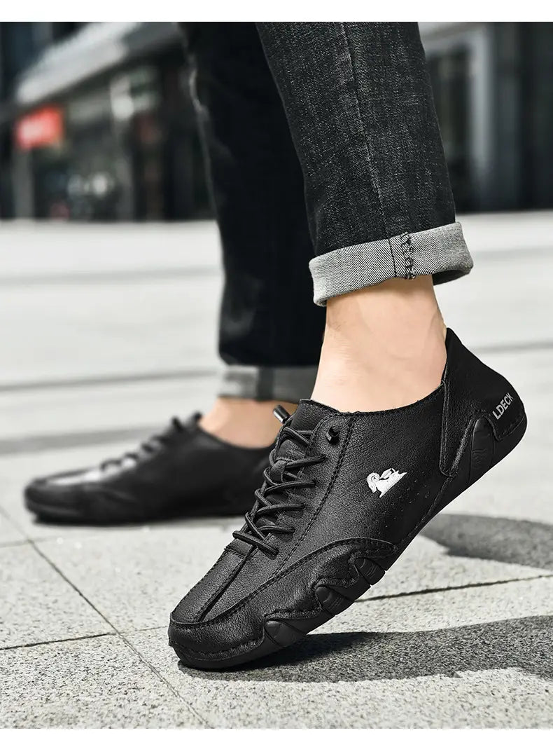 baskets décontractées en daim gris pour homme, dotées d’un laçage en noir avec un logo blanc discret sur le côté et d’une semelle en caoutchouc texturée.