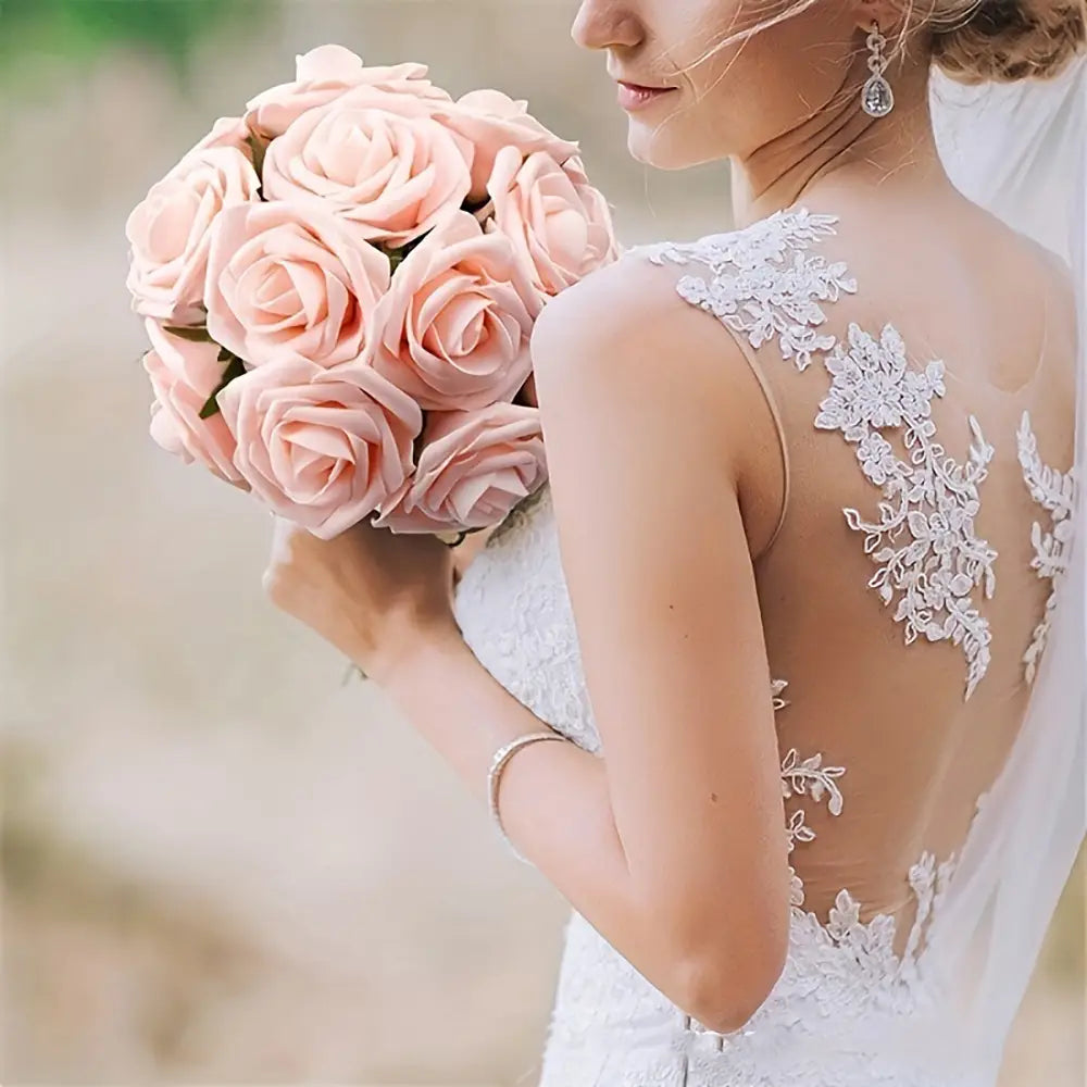 Un bouquet délicat de roses de fleurs artificielles rose tendre, avec des tiges tenues par une mariée, pour la décoration.