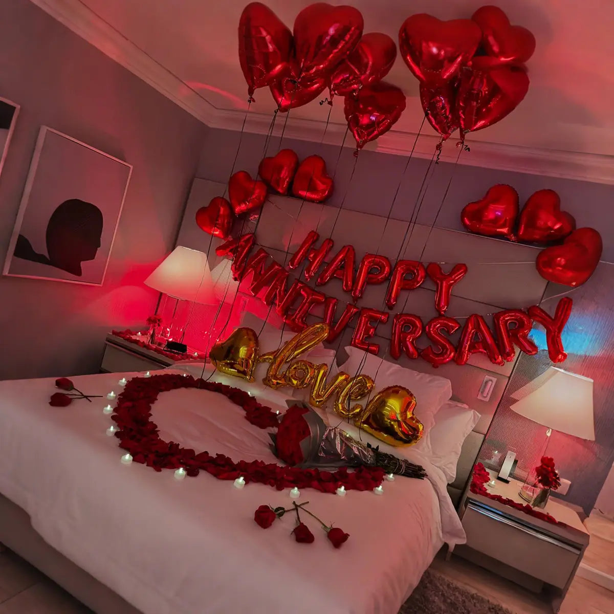 anniversary decoration set featuring red heart-shaped balloons and gold foil lettering spelling happy anniversary adorning a bed.