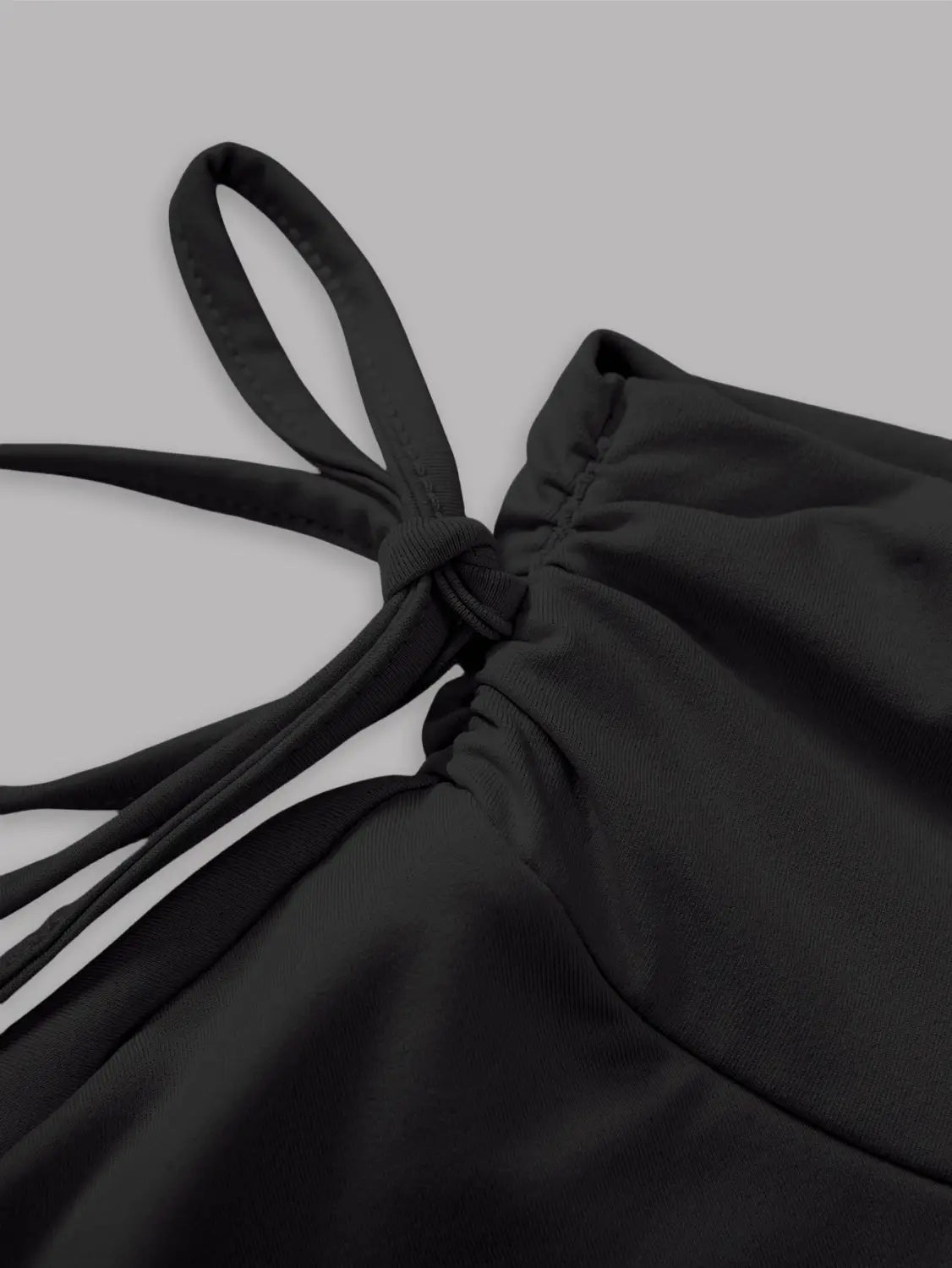 black fabric top with a tied knot detail at the neckline paired with a black high waist ruffle mini skirt.