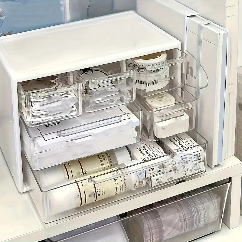 Organisateur de bureau en plastique blanc avec tiroirs transparents et couvercle blanc, disposant avec soin des rouleaux de ruban washi.