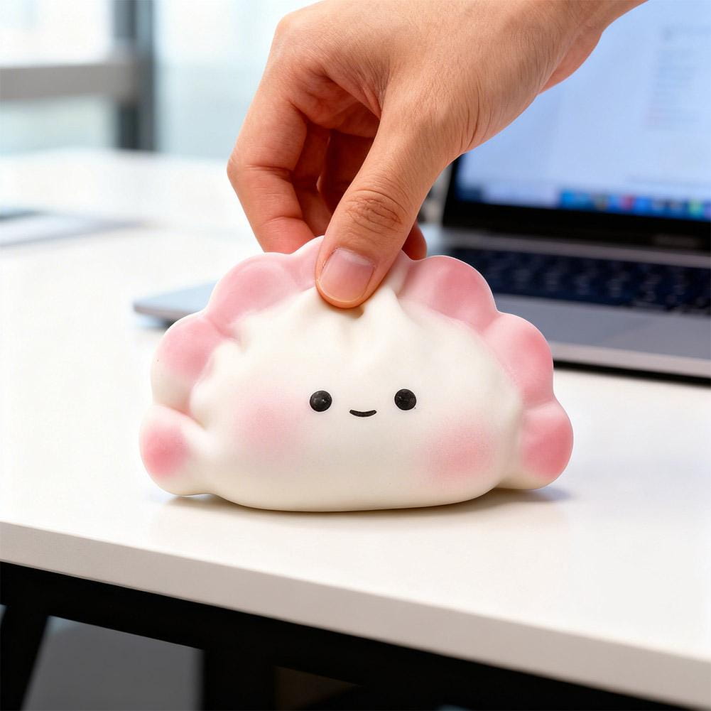 Un juguete blando en color blanco y rosa con forma de dimsum para aliviar el estrés, elaborado con material flexible, diseñado para juguetear y aliviar el estrés.