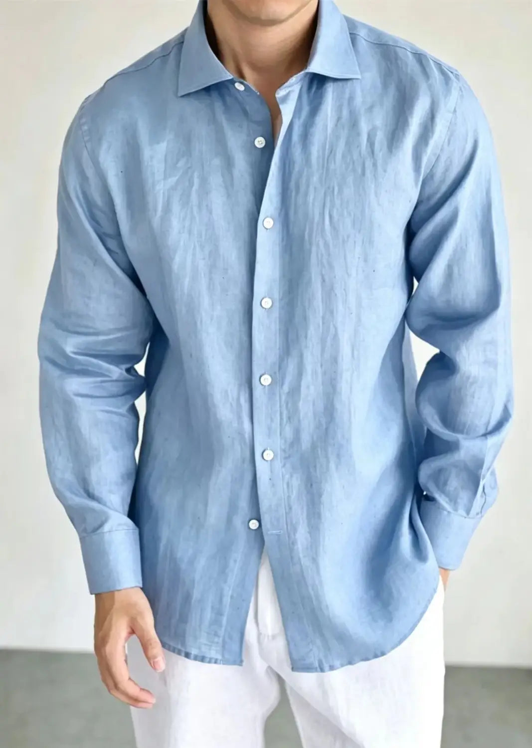 A light blue men cotton linen casual button down shirt with long sleeves, a classic collar, and white buttons.
