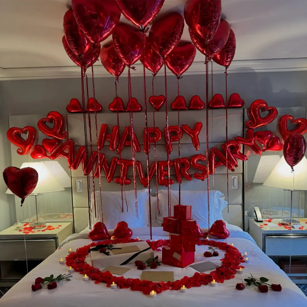 anniversary decoration set featuring red heart-shaped balloons and a happy anniversary balloon banner hanging above the bed for a romantic festive display