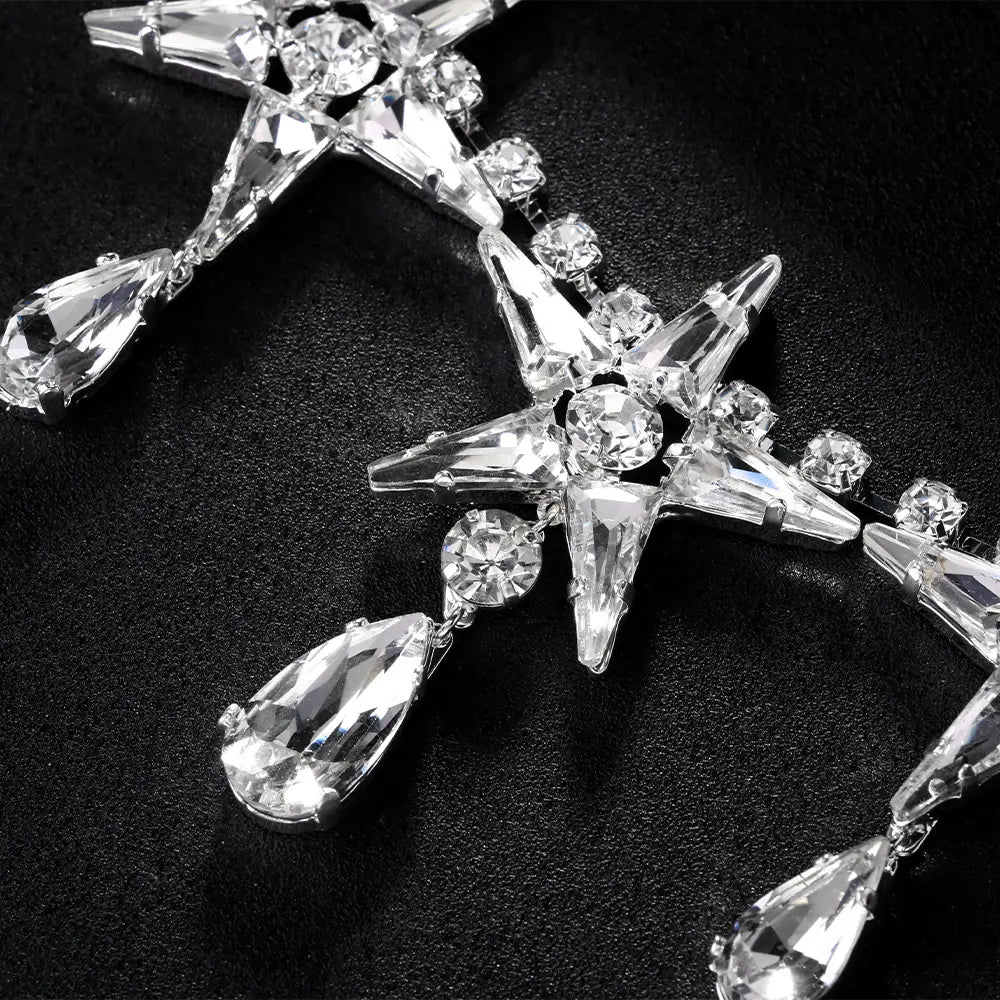 Ein funkelnder silberfarbener Ohrschmuck in Sternform, verziert mit klaren facettierten Kristallen und baumelnden Tropfenanhängern aus der Kollektion „Crystal Star Choker Necklace“.