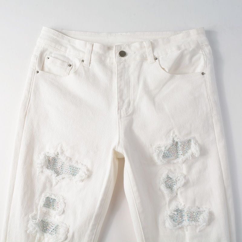 Jean en denim blanc à coupe ajustée, présentant des déchirures au niveau des cuisses et des genoux, ornées d’un effet scintillant, appelé « jean blanc délavé en strass pour hommes ».
