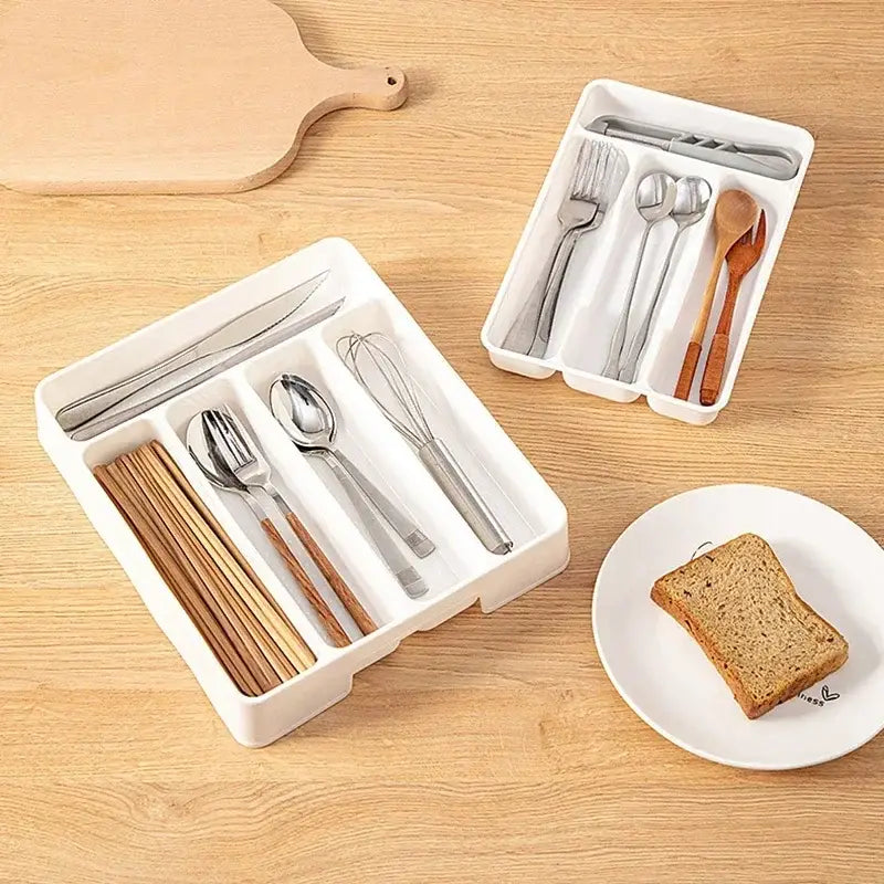 Organisateur de tiroir à couverts en plastique blanc, avec des compartiments pour couteaux, fourchettes, cuillères, baguettes et un fouet, conçu comme un plateau de cuisine.