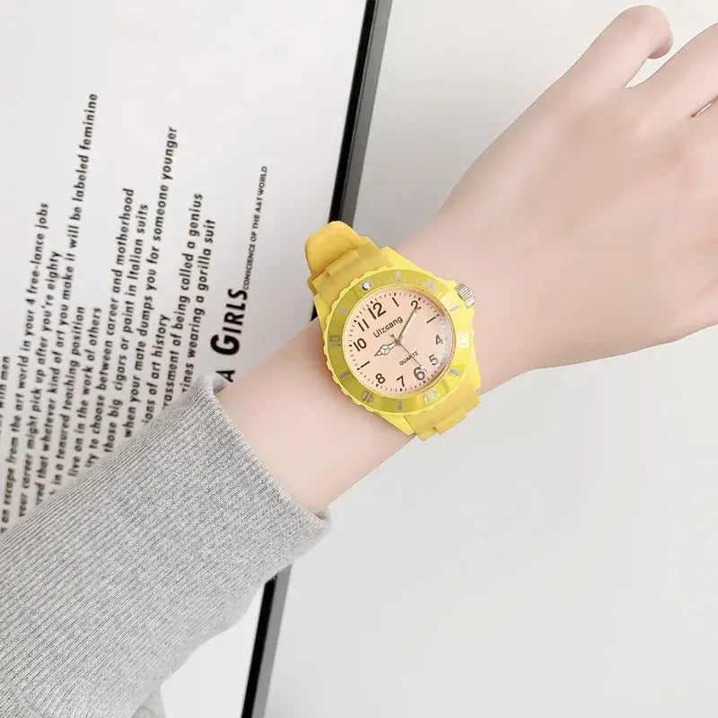 Kids silicone quartz watch with a bright yellow silicone strap, pink face, and white numerals designed as a colorful jelly wristwatch.