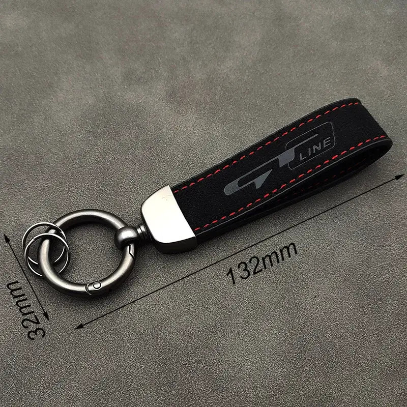 Schwarzer Lederschlüsselanhänger der GT Line aus Wildleder mit roter Steppnaht und silbernem Metallschloss mit eingeprägtem Logo.