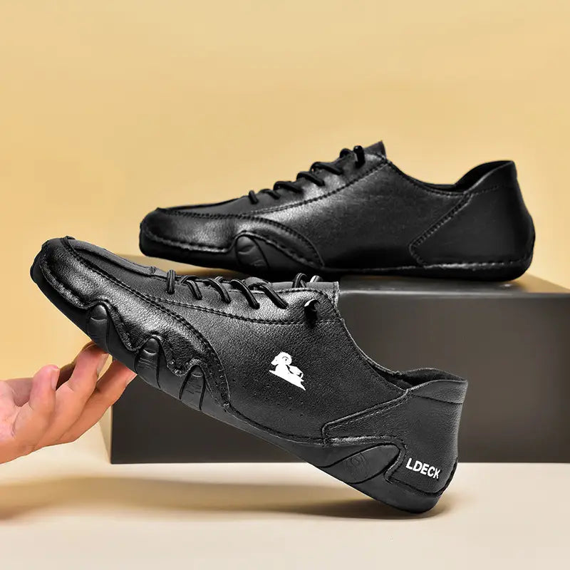 baskets décontractées en daim gris pour homme, dotées d’un laçage en cuir noir avec un logo blanc et d’un marquage ldeck sur le côté.