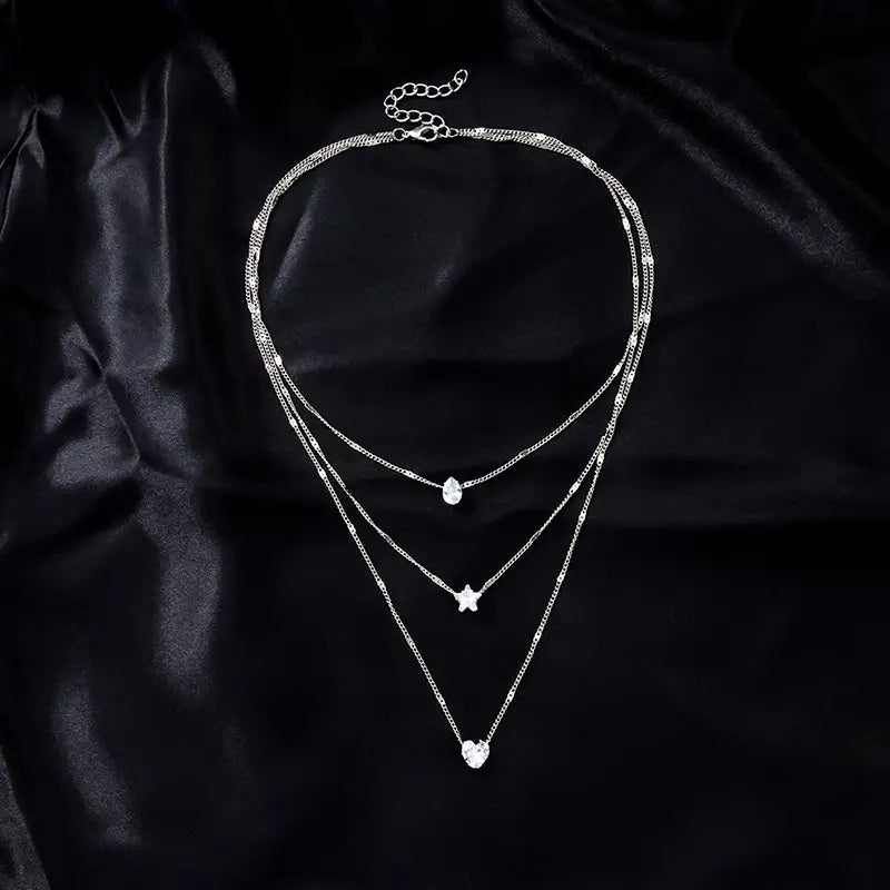 Silver zircon layered pendant necklace for women featuring three delicate chains with teardrop star and heart-shaped charms.