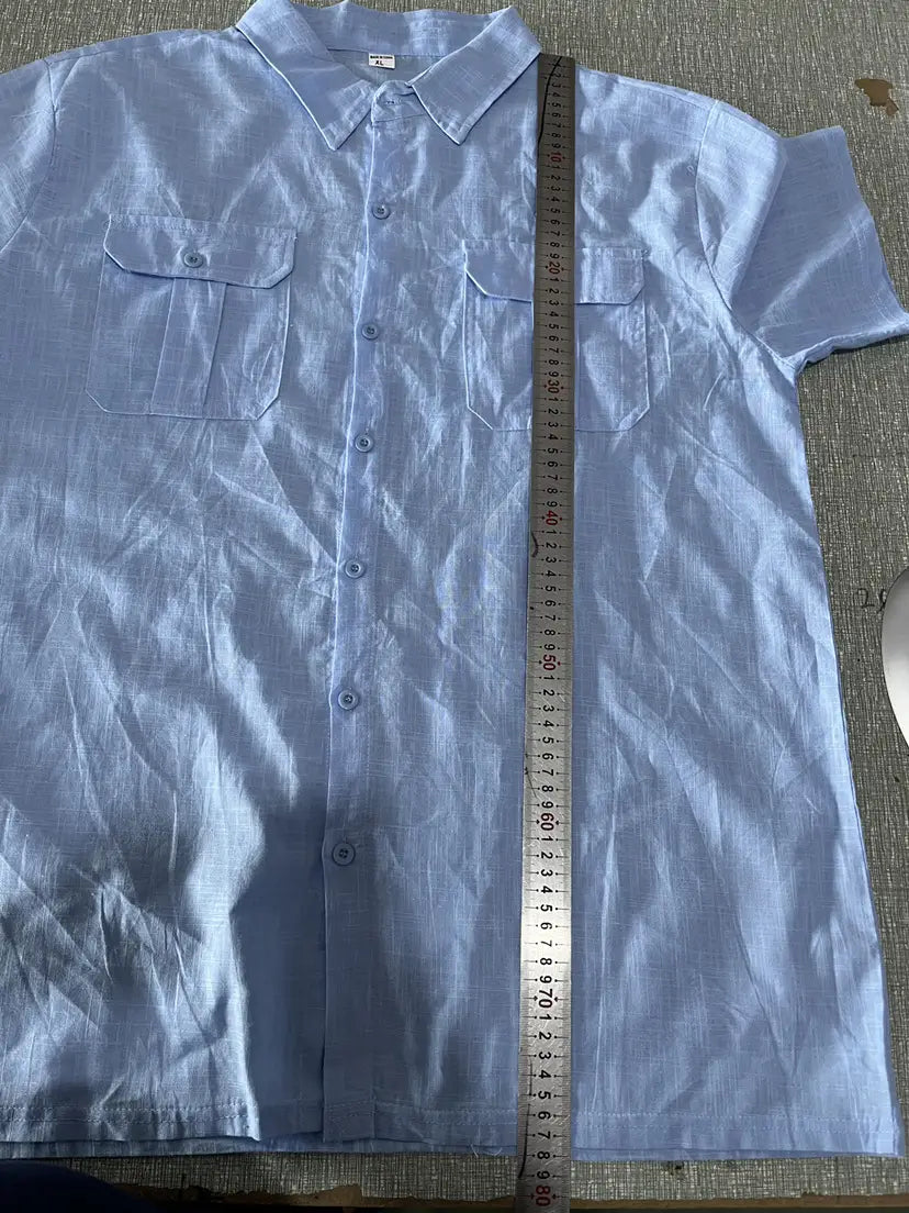 A light blue men linen short sleeve shirt with two chest pockets and a collar made of textured fabric for casual summer wear.